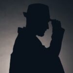 Silhouette of a man with trilby hat and briefcase under arm