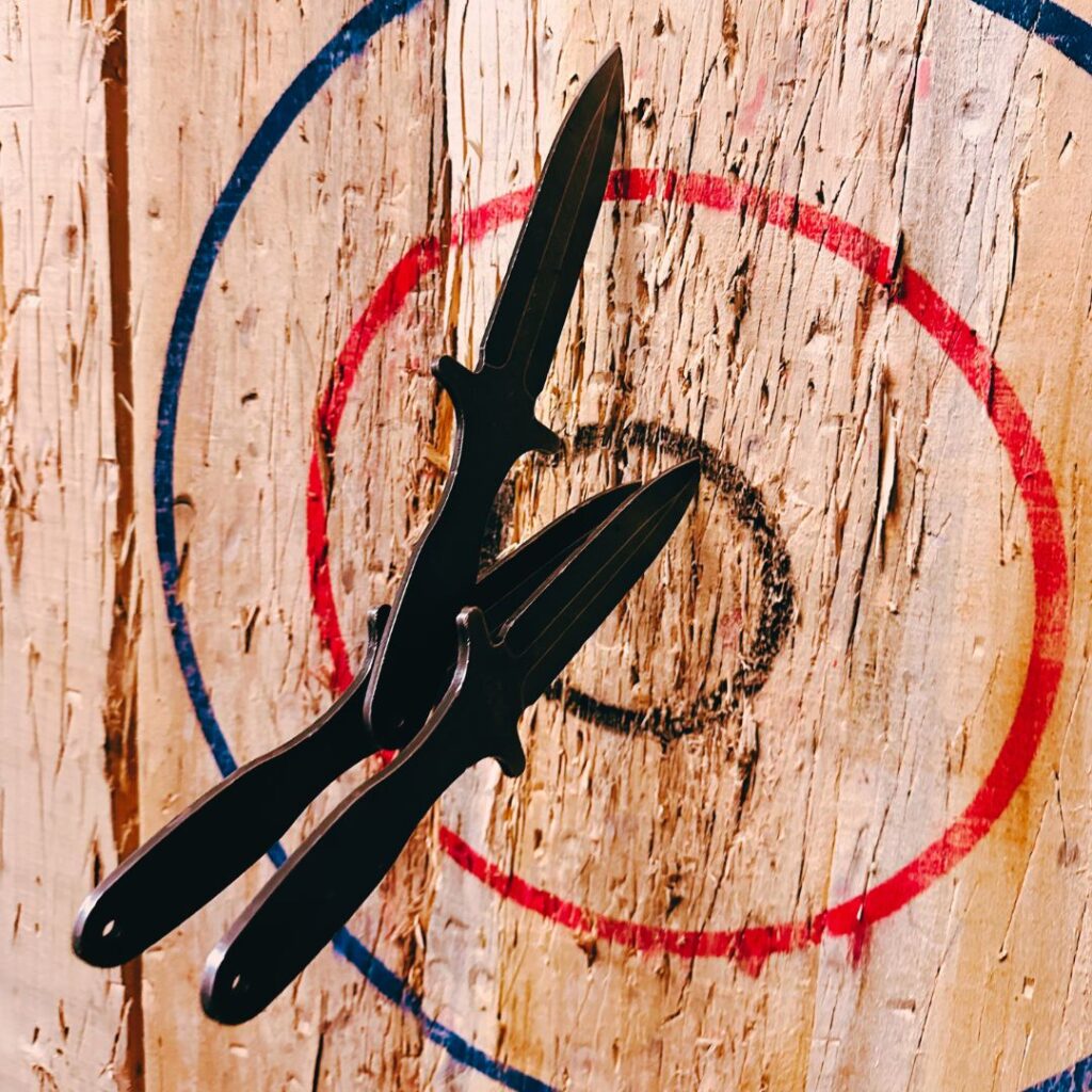 Three throwing knives stuck in a target at the Houston axe throwing venue