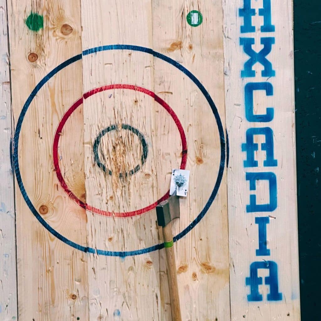 An axe stuck in a playing card attached to a wooden target for some competitive axe throwing