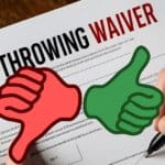 Someone signing an axe throwing waiver with a large red thumbs down and green thumbs up in front