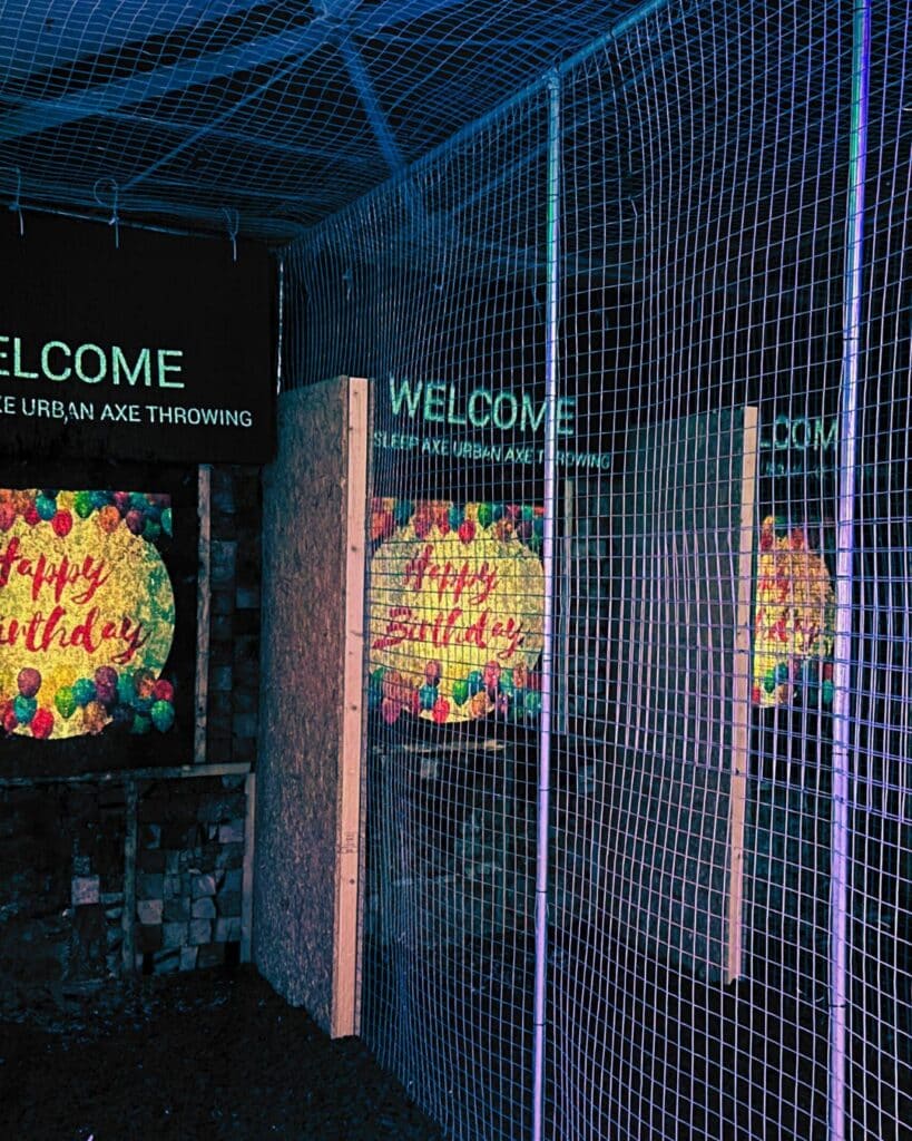 An axe throwing lane with wired safety caging on the side and ceiling