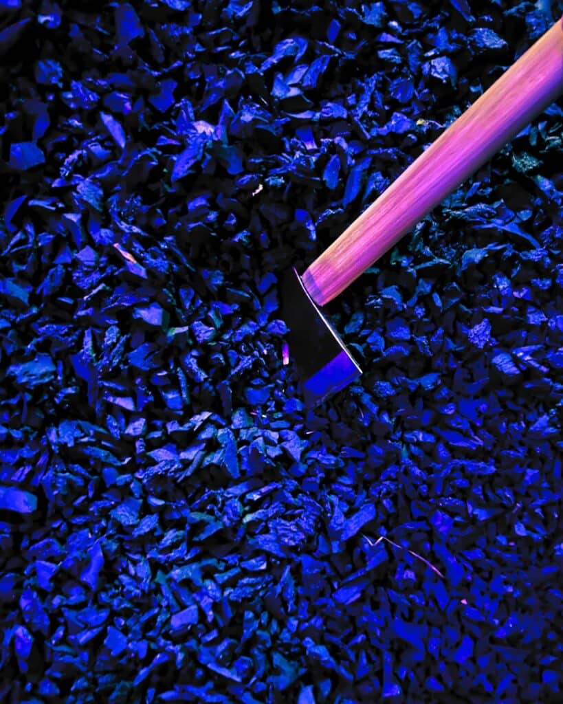 An axe in a pile of rubber chippings like those used for safety in children's playgrounds etc