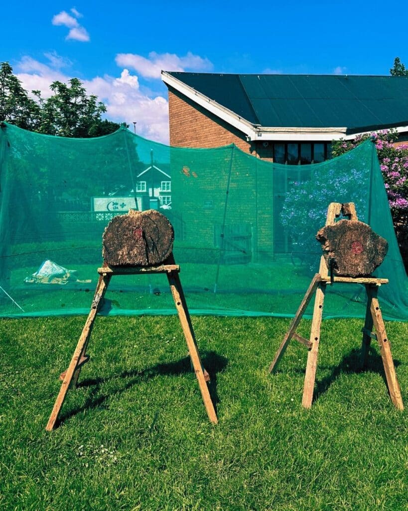 Two axe throwing targets in the foreground with safety nets behind