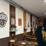 Axe inspector silhouette in front of the inside of the Valencia axe throwing bar